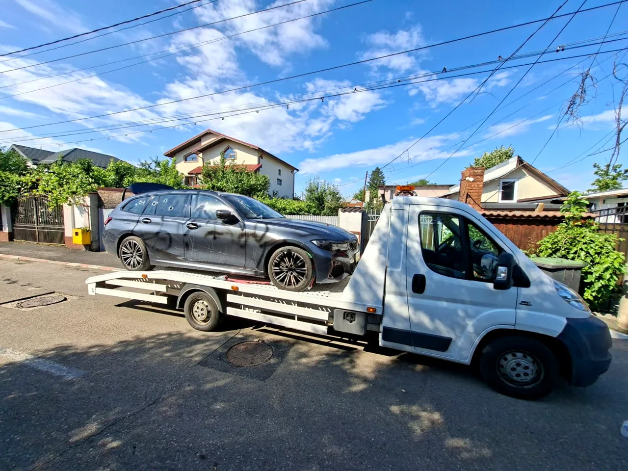 Platformă de tractare cu un autoturism argintiu, fotografiată ziua