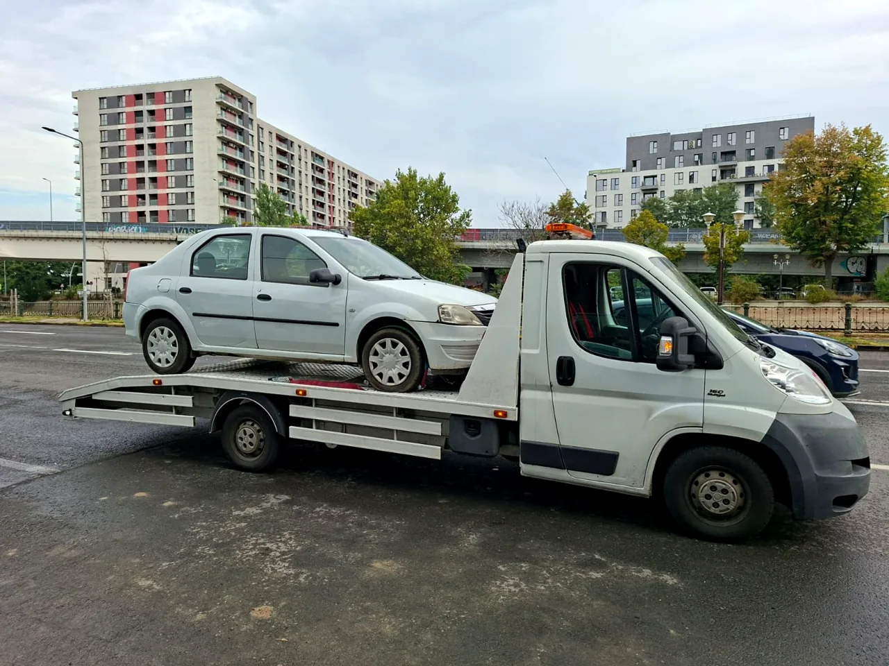 Autoturism transportat pe platformă, în lumină de zi